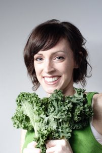 smiling woman holding kale leaves