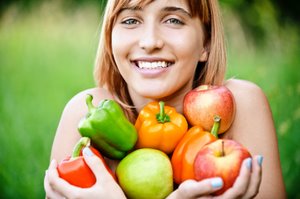 smiling woman with capsicums and apples